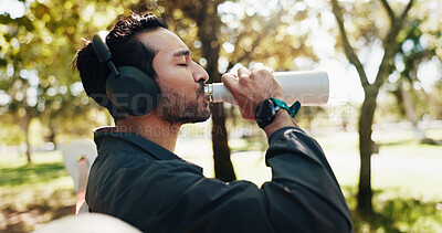 Buy stock photo Break, drinking water and music with man in park for exercise, fitness or running routine. Headphones, hydration and streaming with athlete or runner outdoor in nature for recovery, relax and rest