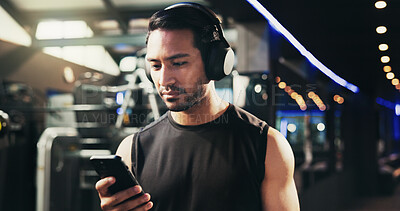 Buy stock photo Man, phone and headphones at gym for training, streaming and check stats for exercise routine. Person, smartphone and listening to music, subscription and mobile app with click at fitness club