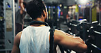 Back, exercise and man in gym, fitness and body workout with training, routine and commitment. Person, healthy and athlete in wellness center, bag and walking with practice, endurance and challenge