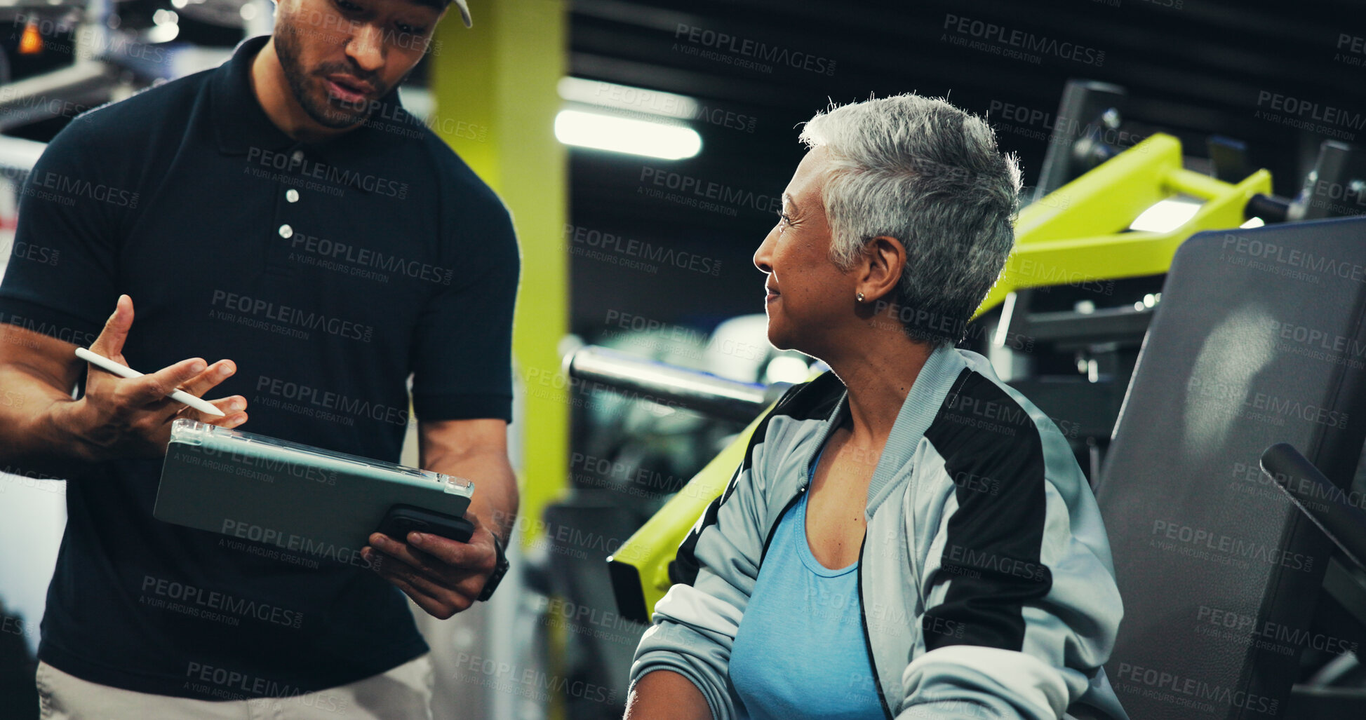 Buy stock photo Talking, man and personal trainer with tablet, woman and showing workout progress, fitness and online. Health club, people and explaining training routine to mature client, instructor and tech in gym