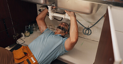 Buy stock photo Man, plumber and repair in kitchen, pipe and sink with search for leak, problem solving and fix in home. Person, handyman and check for water, drain and solution on floor for maintenance at apartment