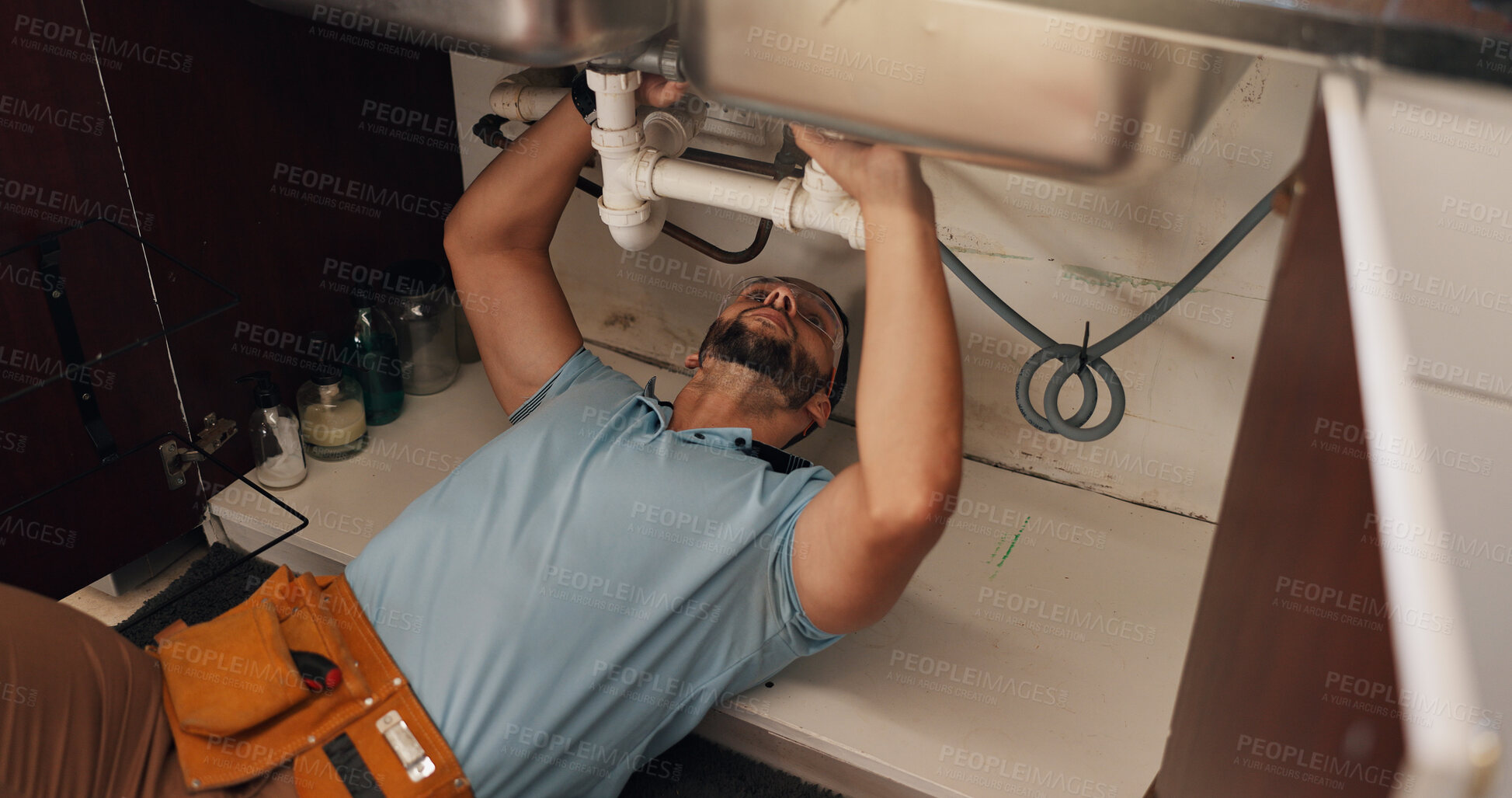 Buy stock photo Man, plumber and repair in kitchen, pipe and sink with search for leak, problem solving and fix in home. Person, handyman and check for water, drain and solution on floor for maintenance at apartment