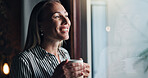 Thinking, coffee and relax with woman at window of living room for reflection, idea and smile. Happiness, memory and future with female person and drink at home for vision, peace and inspiration