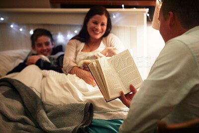 Buy stock photo Son, bed and father reading, mother and night with hobby and activity with happiness and family. Parents, home and boy with mama and dad with book and peaceful with joy, storytelling and literature