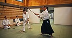 Dojo, class and mentor in Aikido training in gym with wood sword Japanese martial arts and fight exercise in wellness studio. Learning, sport and weapon with people and strike practice for defence