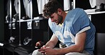 Football, player and man with phone in locker room for text message, check notifications and match break. Sports, athlete and relax with smartphone for social media scroll, online news or mobile chat