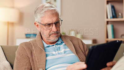 Buy stock photo Senior man, tablet or reading with glasses on sofa for ebook, knowledge or online news at home. Mature, male person or pensioner with technology on couch for research, story or digital novel at house