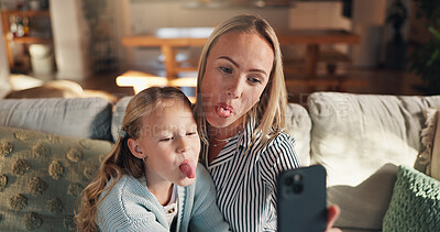 Buy stock photo Mom, girl and funny face with selfie on sofa, tongue or happy with care, love and bonding in family home. Woman, mother and daughter with photography, comic joke and hug on social media at apartment