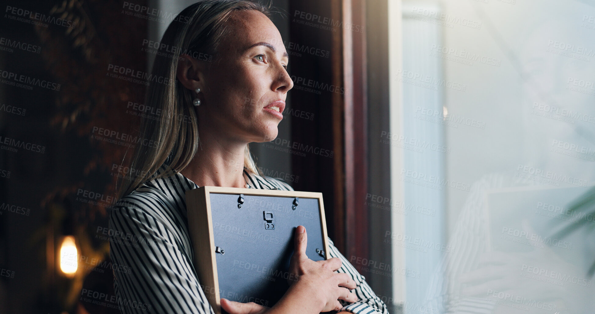Buy stock photo Woman, picture and sad by window with memory, mourning and regret or loss of loved one at home. Female person, widow and hug photo frame with sorrow at house with nostalgia, lonely and reflection