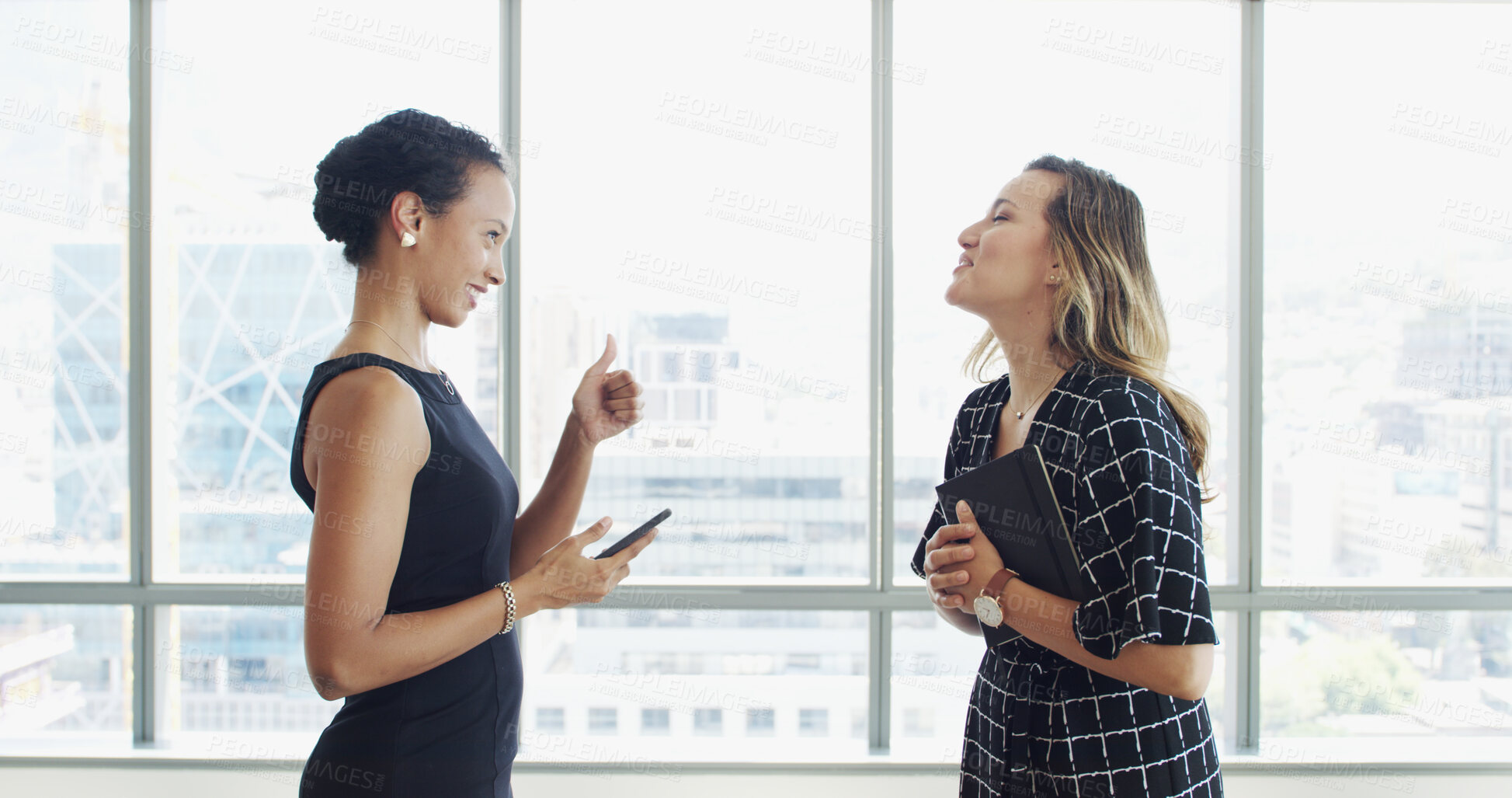Buy stock photo Business women, discussion and thumbs up with smile in lobby for agreement, deal or yes at company. People, partnership and phone with profile, sign or thank you for collaboration at insurance agency