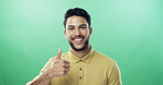 Portrait, man and smile with thumbs up in studio for agreement, thank you and good news. Mockup space, person and like emoji of yes feedback, vote sign and opinion of announcement on green background