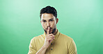 Portrait, man and quiet for secret in studio for gossip, privacy sign and silence for rumor. Person, mockup space and hand gesture for mystery, confidential news and announcement on green background