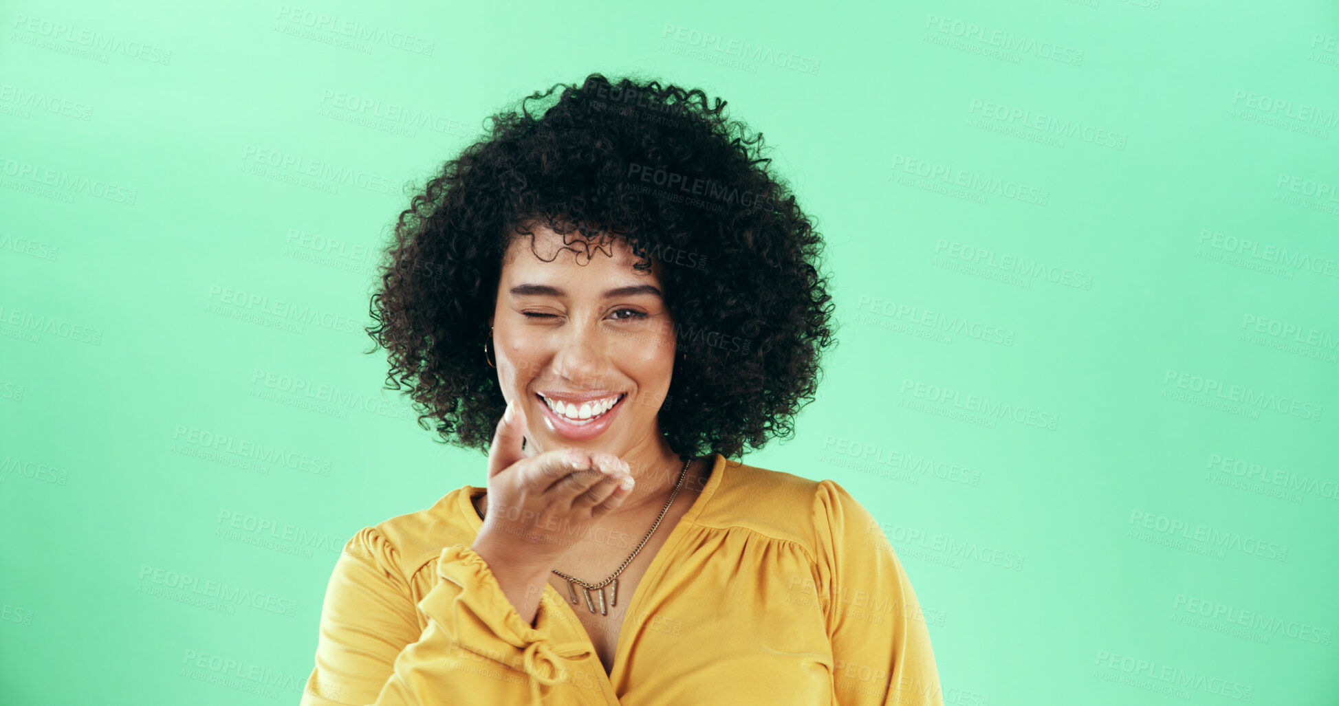 Buy stock photo Portrait, blow kiss and woman in studio, winking and confident personality on green background. Face, happy person and model with hand gesture, smile and symbol with love, emoji and romantic