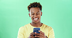 Happy black man, phone and texting in studio with laugh, funny chat and meme by green background. African person, smartphone and click for comic video, mock up space and social media on mobile app