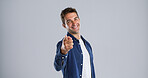 Portrait, pointing to you and man in studio, smile and choice with confidence on gray background. Face, happy person and model with hand gesture, opportunity and decision with sign up and selection