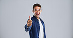 Happy man, portrait or thumbs up in studio for good job or well done on a gray background. Friendly, male person or model with smile, like emoji or yes sign for thank you or agreement on mockup space