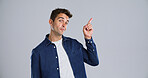 Pointing, portrait and man in studio, opportunity and announcement on gray background. Person, mockup space and model with hand gesture, promotion and discount deal with sales, decision or confidence