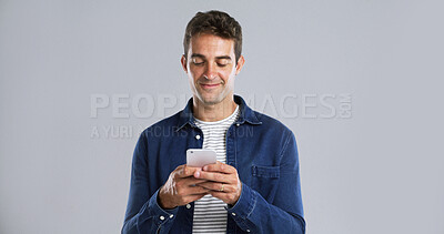 Buy stock photo Man, smartphone and typing for communication in studio, reading text message or web search. Writing email, notification or social media update for comment, smile and mobile app on white background
