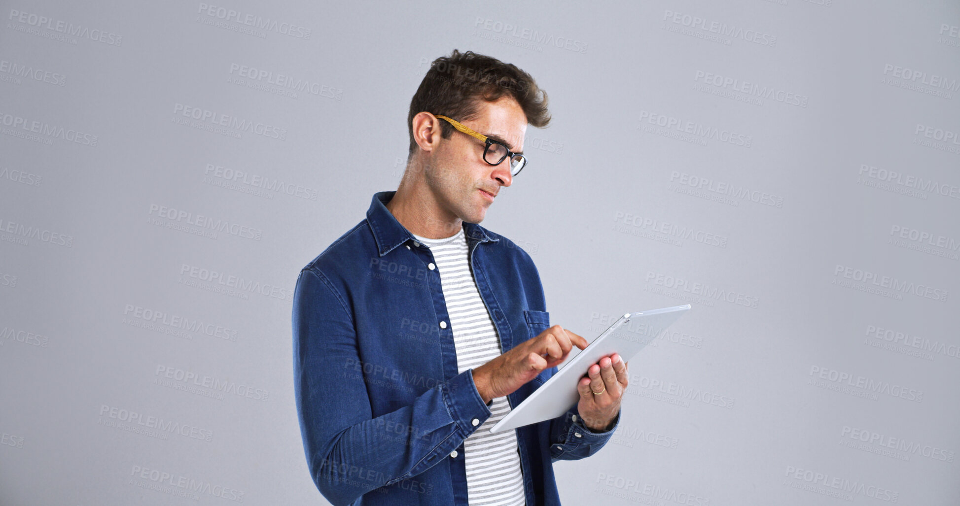 Buy stock photo Glasses, journalism and tablet with editor man in studio for proofreading article of online magazine. App, editing and website post with freelance journalist on white background space for publishing