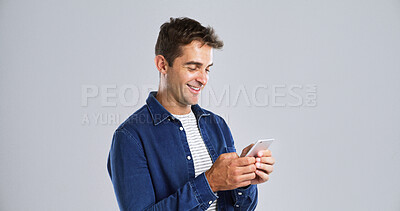 Buy stock photo Smile, mobile and man in studio for typing, text or reading message on white background. Phone, happy person and check email online on app for forum post, play game or social media with mockup space