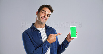 Buy stock photo Man, portrait and phone pointing to green screen in studio for website, mockup space and white background. Student person, user or model with smile, smartphone or software app for university schedule