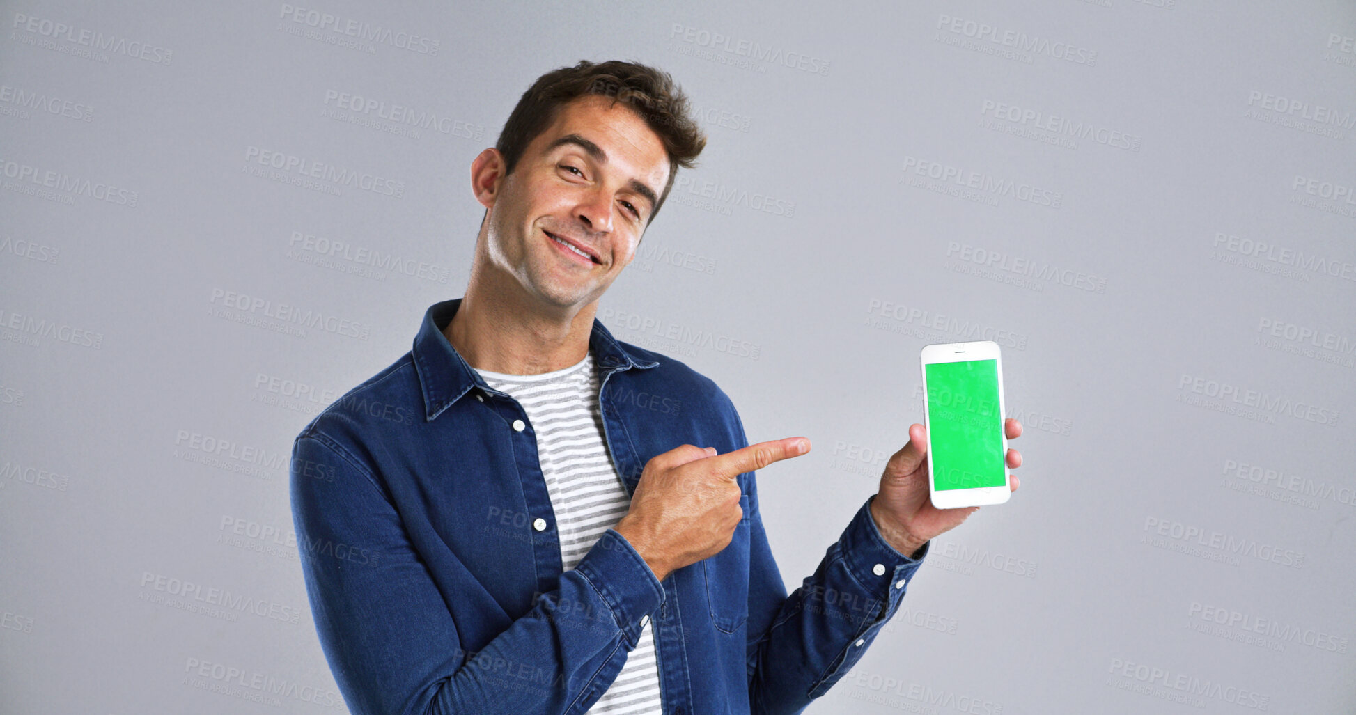 Buy stock photo Man, portrait and phone pointing to green screen in studio for website, mockup space and white background. Student person, user or model with smile, smartphone or software app for university schedule