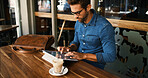 Business, man and typing on tablet at cafe for online research, coffee break and remote work. Freelancer, person and scroll on digital tech at bistro for networking, calendar app and check schedule