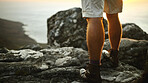 Legs, man and hiking with back view of ocean on vacation, holiday and adventure in nature. Rocks, shoes and person trekking on mountain for exploration, tourism and travel for hobby by cliff at sea