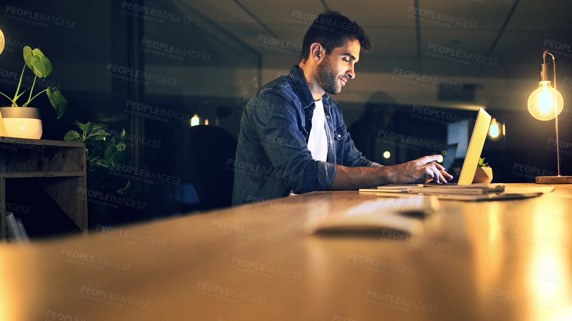 Buy stock photo Laptop, night and typing with business man in office for deadline or feedback on creative report. Computer, desk and research with design employee in dark workplace for productivity at zero hour