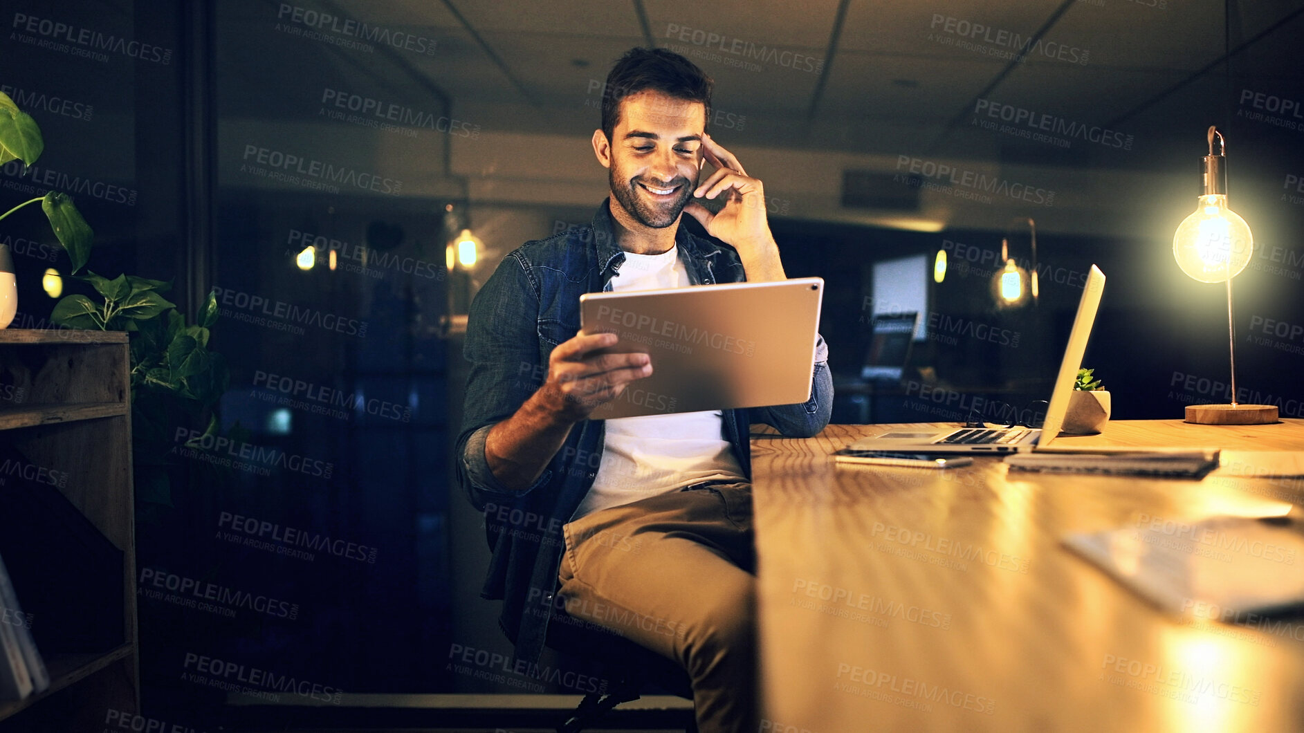 Buy stock photo Dark, smile and man in office, tablet and email with graphic designer, internet and web proposal. Person, night and freelancer with deadline, tech and app for creative project and online reading