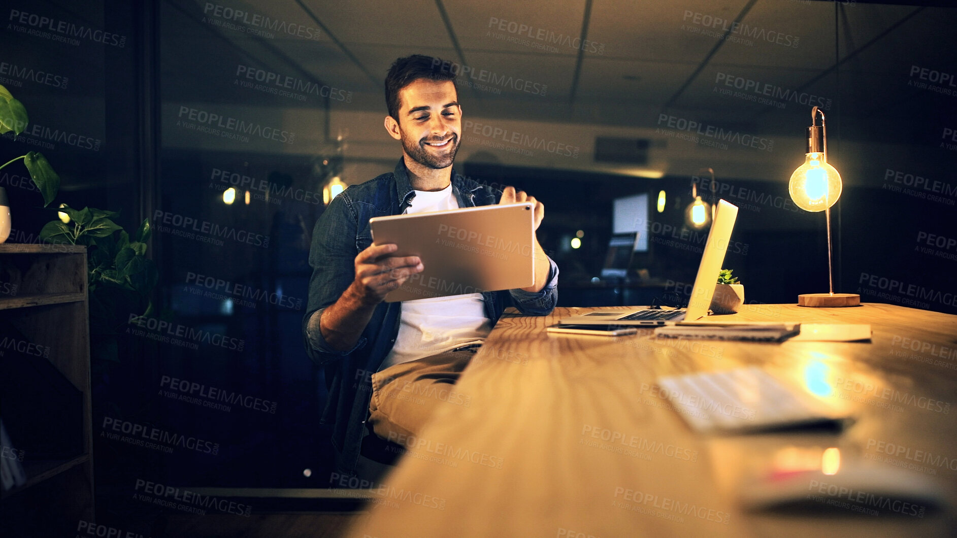 Buy stock photo Night, typing and man in office, tablet and smile with graphic designer, internet and online reading. Person, evening and employee in workplace, tech and app for creative project and social media