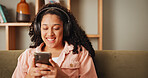 Girl, phone and happy on sofa with headphones, texting and contact for funny chat in living room. Woman, smartphone and laugh with listening to music, streaming and social media on couch at apartment