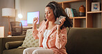 Girl, phone and dancing on sofa with headphones in home, smile and radio at night in living room. Woman, smartphone and happy with listening to music, streaming and rhythm on couch at apartment