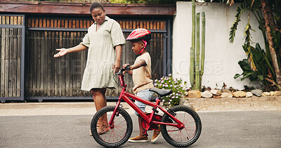 Buy stock photo Support, learning and boy on bicycle with mom on street of neighborhood for child development. African woman, love or black kid with trust, help or single mother teaching son how to ride bike outside