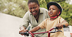 Support, teaching and boy on bicycle with mom on street of neighborhood for child development. African woman, smile or black kid with trust, help or single mother to learn how to ride bike outside