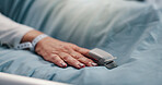 Hand, person and pulse oximeter on hospital bed to measure blood levels, monitor and recovery. Closeup, senior patient and resting with medical machine, track oxygen and critical care from operation