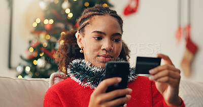 Buy stock photo Christmas, credit card and phone with black woman on sofa in living room for online shopping. Ecommerce, internet and payment checkout with person in home to purchase gift or present on mobile app