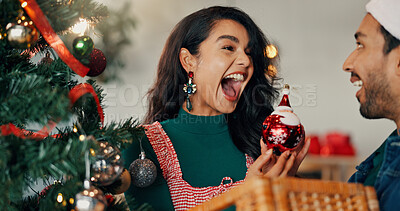 Buy stock photo Christmas, tree and surprise with couple and bauble for festive season, tradition and decoration. Xmas, holiday cheer and celebration with man and woman in living room of home for happy and ornament