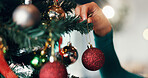 Person, hand and christmas tree with bauble for decor, festive event or december holiday in home. Closeup, ornament or hanging sparkle ball for new year celebration or Santa decorations at house