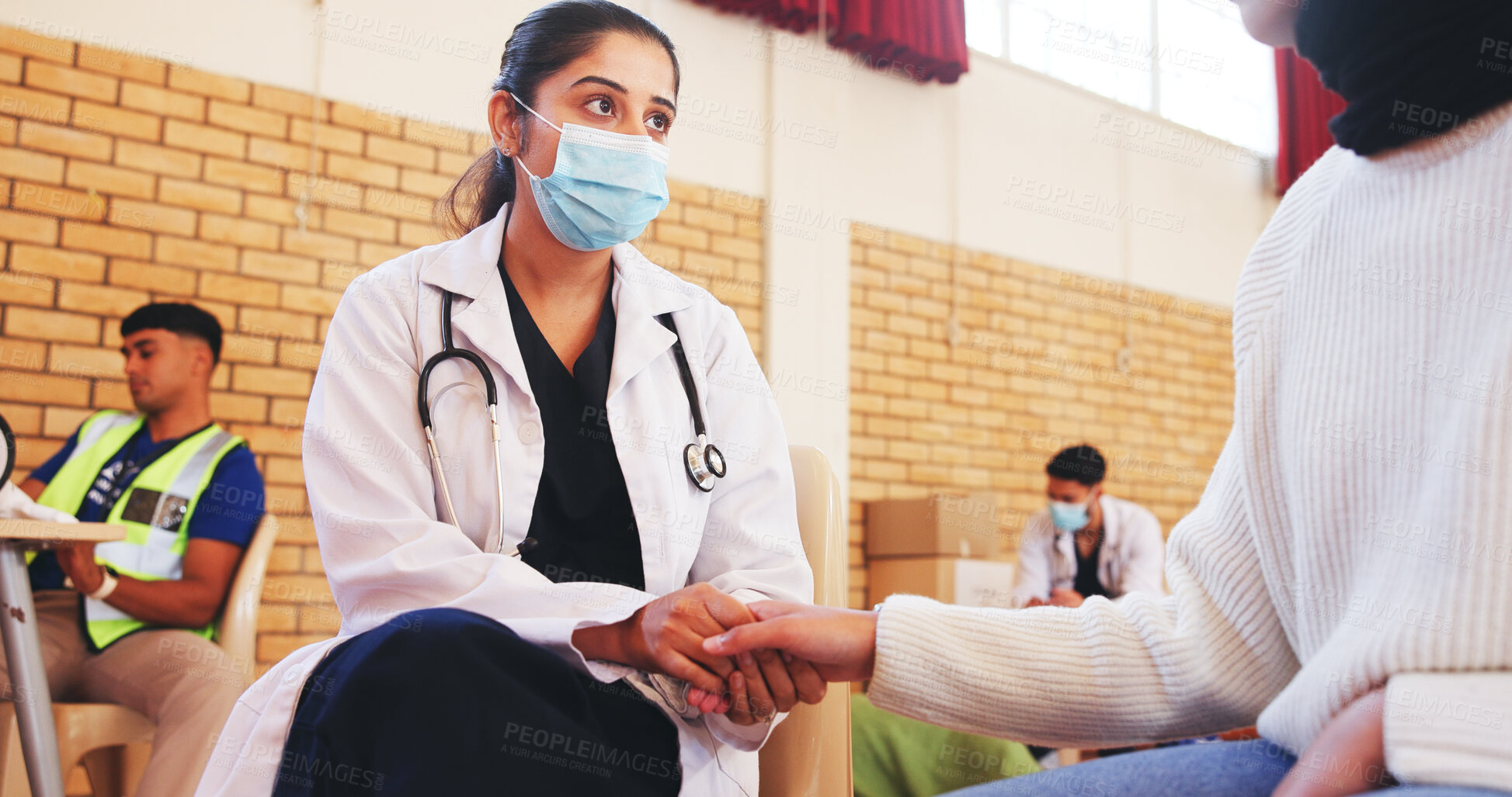Buy stock photo Face mask, support and doctor holding hands with patient for charity, NGO campaign and counselling. Outreach event, nurse and person in community center with healthcare volunteer, advice and help