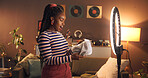 Unboxing, creative and woman with ring light, home and influencer with product to review or website. Live stream, content creator and black person with package for social media, app or promo at night