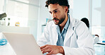 Man, scientist and typing on laptop in lab for research, reading study and medical experiment. Serious, male person and online for project, biotechnology and science article of healthcare information