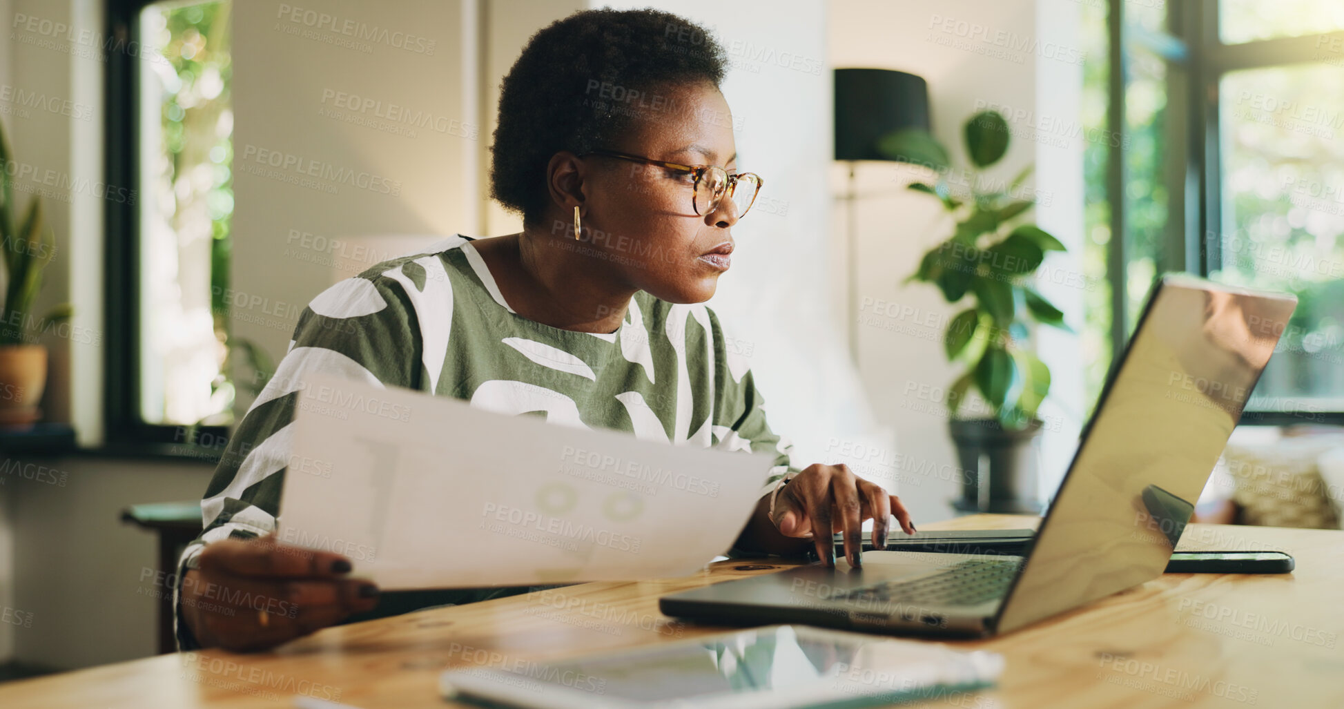 Buy stock photo Black woman, document and typing on laptop at house for accounting, finance report and remote work. Female freelancer, audit and online for financial results, stats paperwork and expenses information