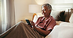 Phone, smile and mature woman in bed with dating app, social media or comedy video on internet. Happy, technology and senior female person with scroll on mobile with cellphone in home for break