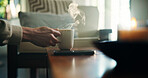 Hand, tea and person in house with steam, warm drink for thirst and relax with herbal beverage in living room. Break, calm and mug on table with hot coffee, espresso or fresh brew in home lounge