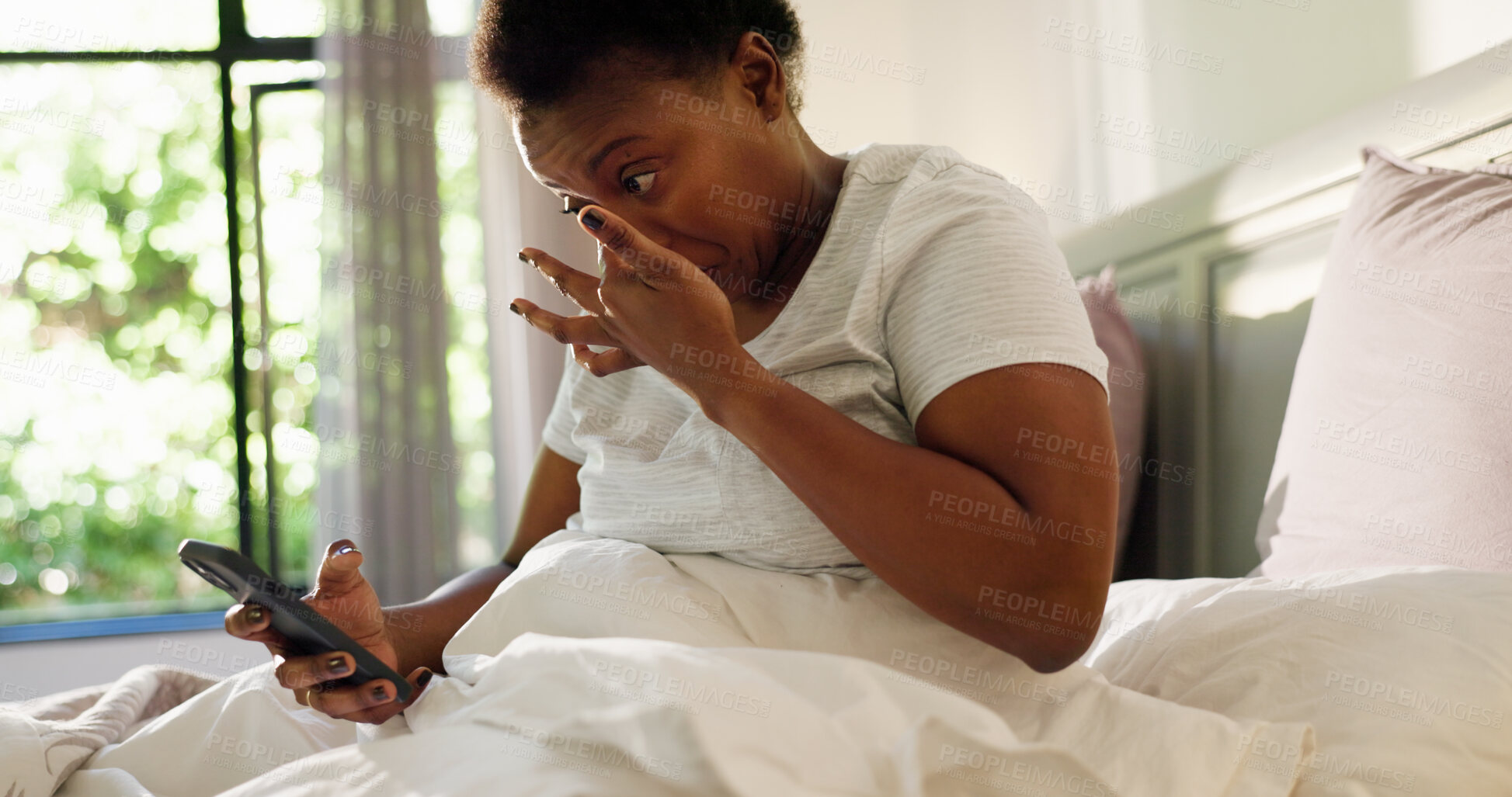 Buy stock photo Black woman, phone and wake up with texting in bed, tired and snooze alarm in morning at home. African person, exhausted and check notification with smartphone, click and mobile app in bedroom