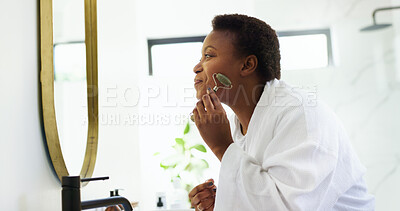 Buy stock photo Jade roller, skincare and black woman in bathroom for wellness, beauty and skin toning. Dermatology, home and person with face tools for cosmetics, grooming and facial for morning routine in mirror