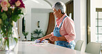 Mature woman, cleaning and wipe table in home for housekeeping, chores or hygiene maintenance. Daily housework, person and disinfect surface with cloth for flower petals, dirt and leaves in house