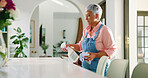 Mature woman, cleaning and spray table in home for housekeeping, chores and hygiene. Housework, person and disinfect surface with chemical detergent in bottle for bacteria, virus and germ prevention