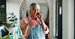 Phone call, housekeeping and woman with supplies in home for contact, networking or communication. Cleaning, cellphone and mature housewife on mobile conversation by sanitizing products in apartment.